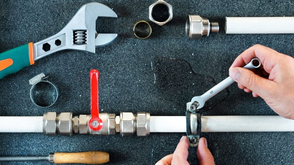 Plumber repairing a pipe valve with an adjustable wrench in Harrisburg