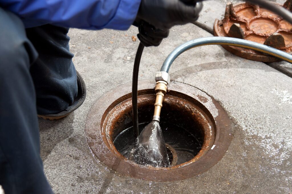 Plumber hydro jetting a sewer line through a manhole in Harrisburg