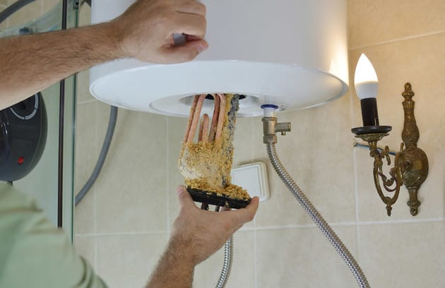 Technician removing mineral buildup from a water heater in Harrisburg