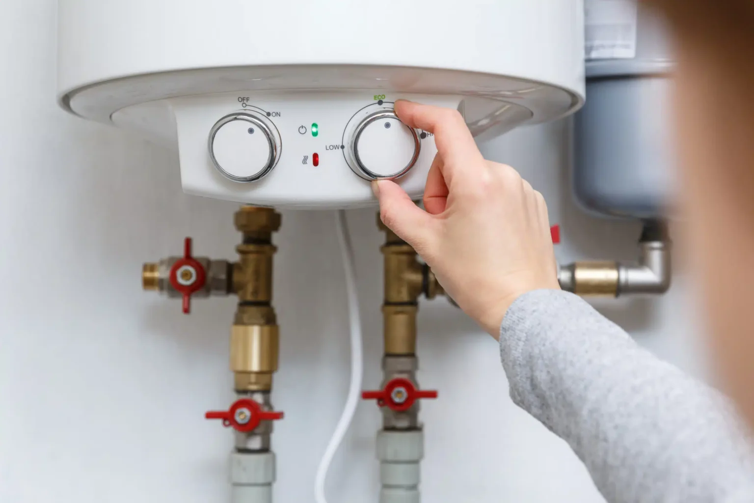 Homeowner adjusting the temperature controls on a water heater in Harrisburg